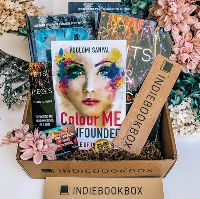 Bookstagram picture and ad of the Indie Book book, a box filled with 4 indie books, bookmarks and a pin surrounded by pink and blue pastel flowers