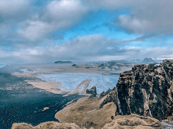 Driving Dyrholaey in Iceland Winter with black sand beach and blue water
