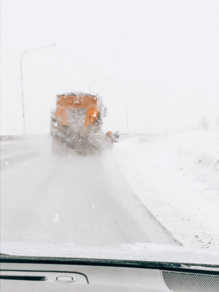 driving in Iceland in winter snow as yellow truck clears the road