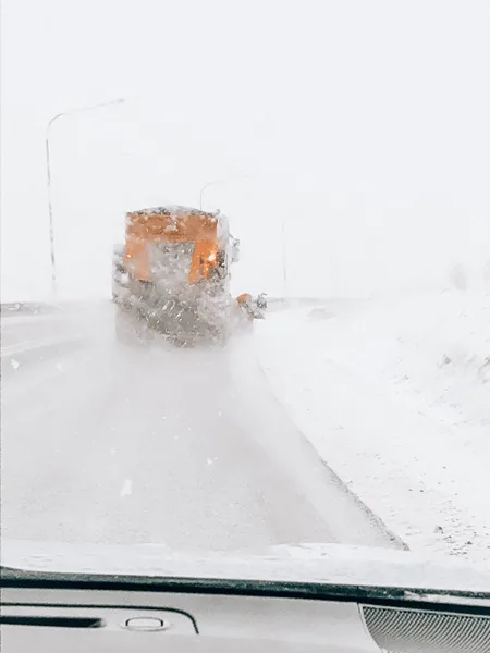 driving in Iceland in winter snow as yellow truck clears the road