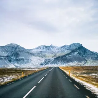 How To Better Prepare For Driving In Iceland In Winter with snowy road and Icelandic mountains