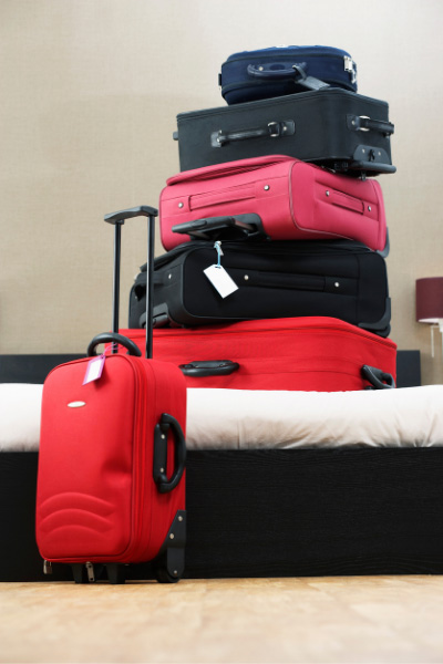 Self Driving In Iceland Pro Bring More Luggage with stack of red, black, and pink suitcases on a bed
