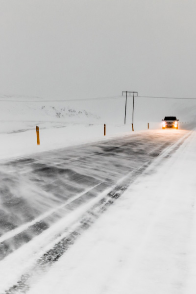 Snow Driving In Iceland Winter with car on an icy and snow road with lights on