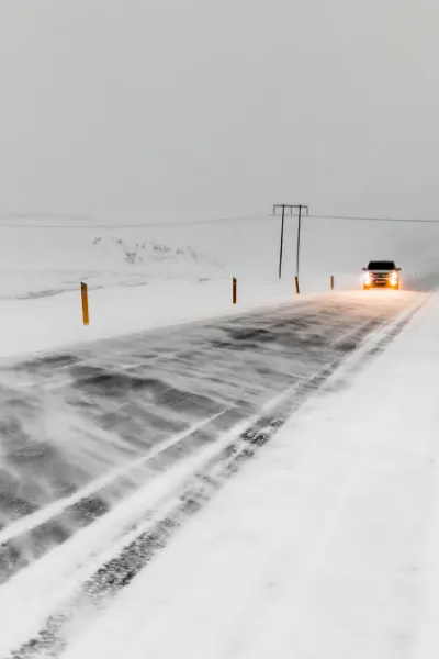 Snow Driving In Iceland Winter with car on an icy and snow road with lights on