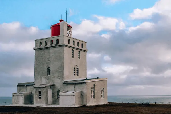 Dyrhólaey Lighthouse in Iceland with gray lighthouse and clouds