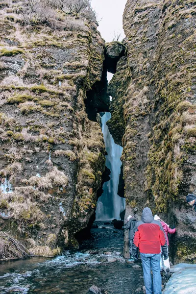 Gljufrabui Waterfall South Iceland with crack between rocks and waterfall in between along with people looking in