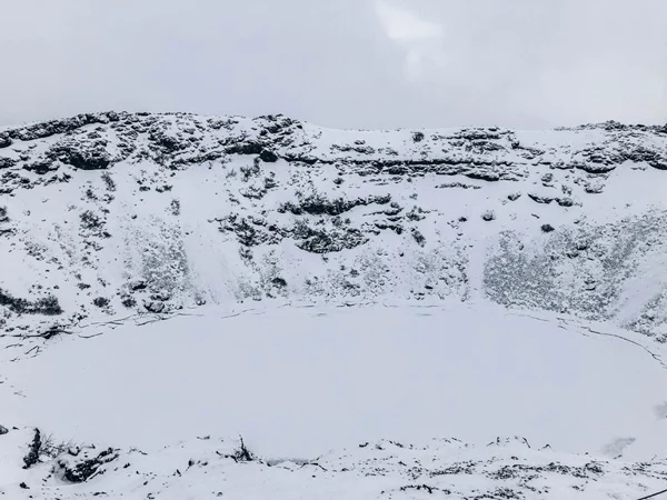 Kerid Crater Iceland in winter with 7-day itinerary and snow; Kerid crater is a hole covered with frozen water and white snow