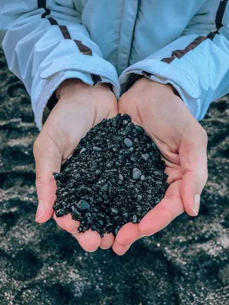 Black lava sand cupped in hands at Reynisfjara Black Sand Beach