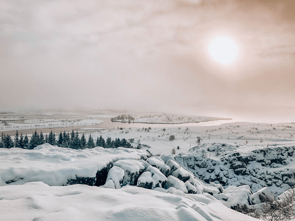 Þingvellir National Park Iceland with snow and sun behind clouds