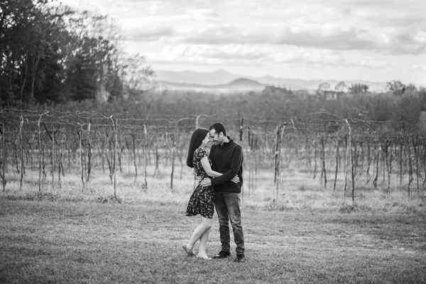 Pros Of Moving To Asheville Wineries black and white photo with brunette white male and female embracing at a vineyard