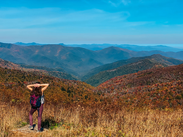 Reasons For Moving To Asheville BRP Hiking Trails with brunette white woman looking out at Black Balsam and Art Loeb Trail