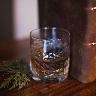 Leather Bound Book Smoked Old Fashioned Recipe with book, green plant, and brown Old Fashioned cockttail