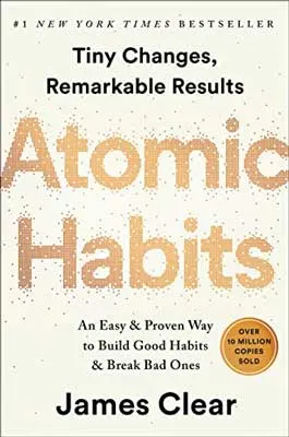 Atomic Habits by James Clear book cover with eggshell background color and golden lettering