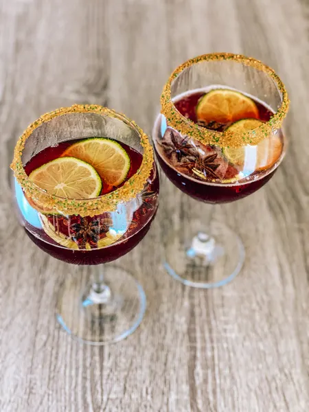Cheerwine Cocktail Bourbon Recipe with two large wine glasses filled with Cheerwine Holiday punch and lime garnishes