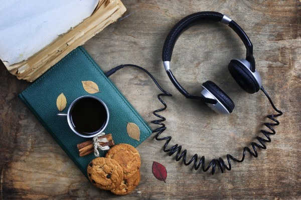 Controversial Book Blog Post Ideas Audiobooks with black headphones attached to a green book