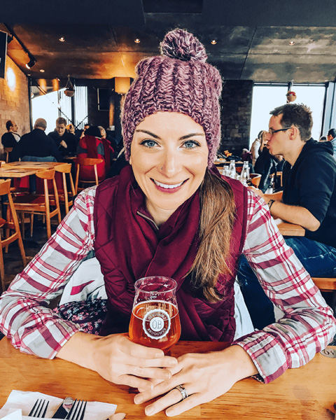 Beer from Olvisholt Brewery Iceland with white brunette female wearing red hat, scarf, and plaid shirt