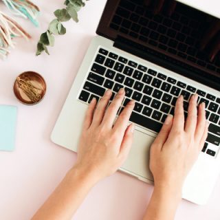 how to start a book blog book blogging 101 with white hands typing on silver laptop and blue notebook