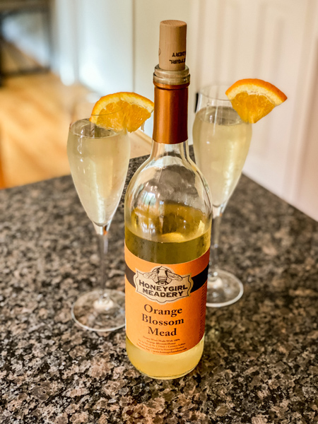Orange Bellini Mead Cocktail Recipe with Honeygirl Mead and two champagne flutes with  orange garnish