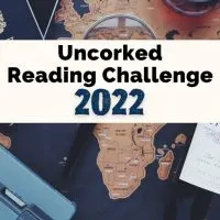 Uncorked Reading Challenge 2022 with bottle of wine, passport, blue old fashioned camera, and maps