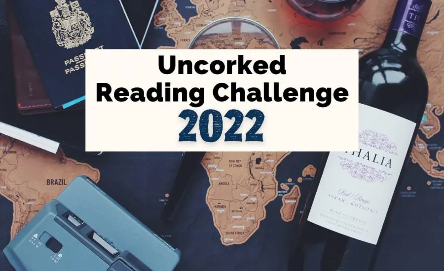 Uncorked Reading Challenge 2022 with bottle of wine, passport, blue old fashioned camera, and maps