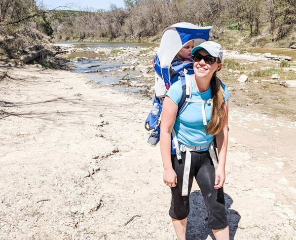 Tori Curran Explore with Tori white, blonde woman hiking with backpack and young child on back in carrier