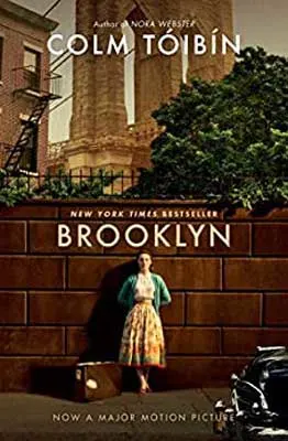 Brooklyn by Colm Tóibín book cover with woman in skirt with green cardigan leaving against a brown stone wall