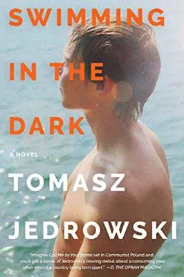 Swimming in the Dark by Tomasz Jedrowski book cover with young white skinned boy with light brown hair in water without a shirt