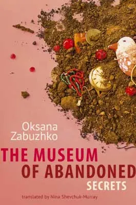 The Museum of Abandoned Secrets by Oksana Zabuzhko book cover with pile of dirt with bird, buried pocket watch, and other items on pink background