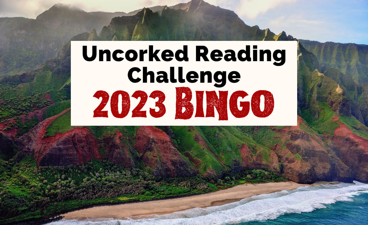 Uncorked 2023 Reading Challenge with image of red and green hill mountain next to brown sand beach with ocean waves