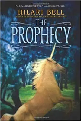 The Prophecy by Hilari Bell book cover with tan unicorn rearing in dark forest with green grass and blue trees