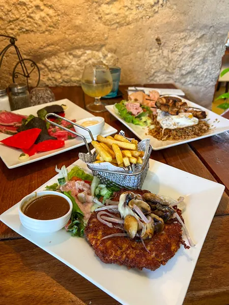 Bistro de Suikertuin Restaurant in Oranjestad Aruba with image of chicken schnitzel, fried rice, and raw tuna with tortilla chips on plates on table
