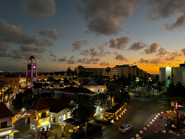 The Vue Rooftop Aruba Restaurant with view from the rooftop overlooking Palm Beach and shopping area at sunset with darkening orange and blue sky with clouds