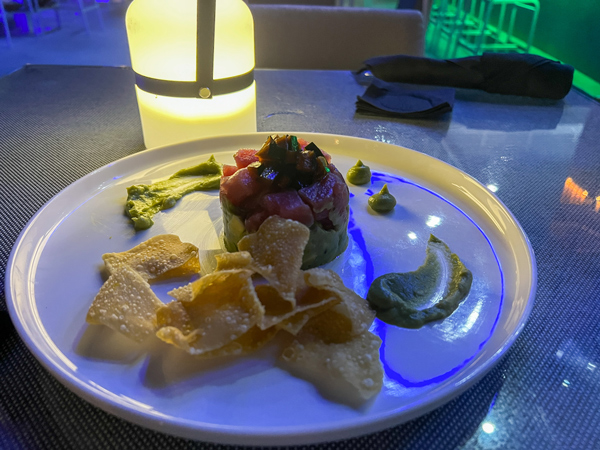 The Vue Rooftop Aruba Restaurant with raw tuna on avocado with tortilla chips on white plate at night