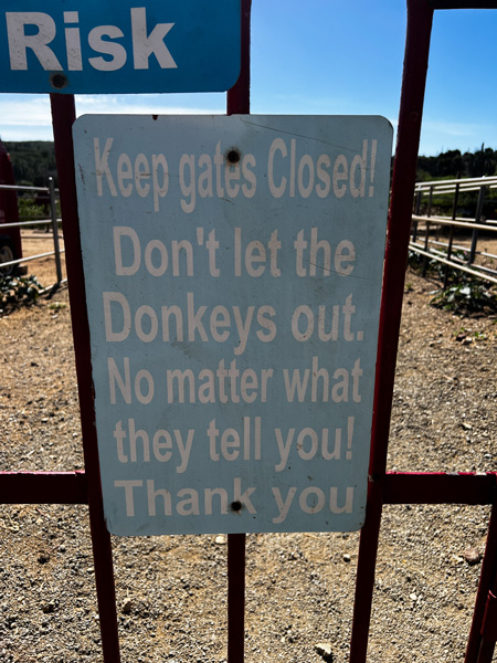 Donkey Sanctuary Aruba Gates with sign that says "Don't let the Donkeys out no matter what they tell you! Thank you!"